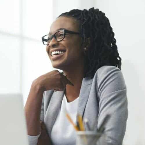 African American Businesswoman Laughing Sitting Against Window In Office
