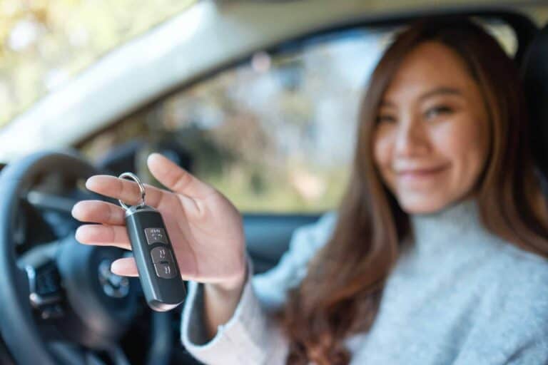 An asian woman holding car key while sitting in the car