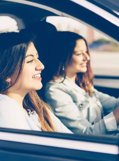 Happy girls friends in a car on trip