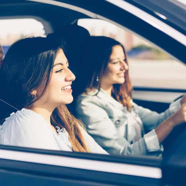 Happy girls friends in a car on trip